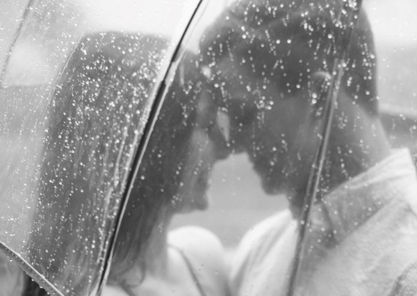 زوجی عاشق زیر باران در زیر یک چتر